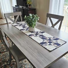 a dining room table with a potted plant on it and a rug in the middle