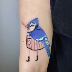 a small blue bird with an umbrella on its back arm, tattoo artist in london