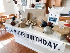 an image of a birthday party setting with balloons and gifts on the table in the kitchen