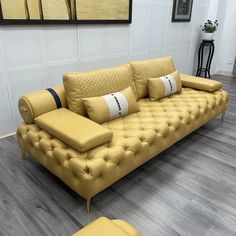 a yellow leather couch and ottoman in a living room with wood flooring on the walls