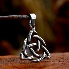 a celtic knot pendant is shown on a piece of wood with a stick in the foreground