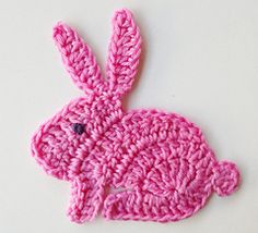 a crocheted pink bunny rabbit sitting on top of a table