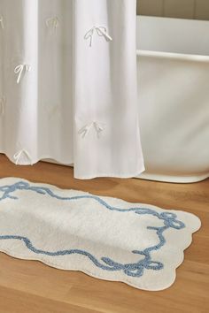 a white bath tub sitting on top of a wooden floor next to a shower curtain