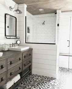 a bathroom with white walls and black and white floor tiles on the floor, along with two sinks