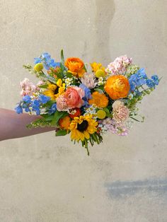 a person holding a bouquet of flowers in their left hand and the other hand with it