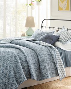 a bed with blue and white bedspread in a bedroom next to a window