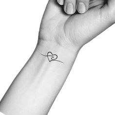 a woman's arm with a small heart tattoo on the left side of her wrist