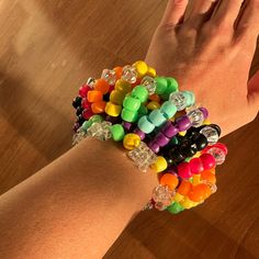 a person's hand holding a bunch of bracelets on top of a wooden table