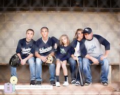 a group of people sitting on top of a bench with baseball bats in their hands