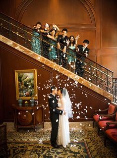 a bride and groom standing in front of a staircase with confetti falling from it