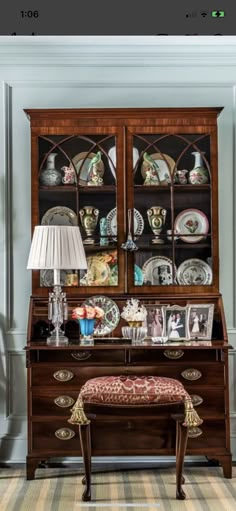 an old fashioned china cabinet with plates and cups on it