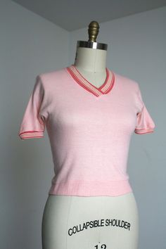 Fantastic hard-to-find knit top from the 1950s. I love finding the more casual daywear like this. This piece is in a wonderful shade of pink! Slight dolman sleeves, cute collar, and fitted waist.  Label: label has worn writing away so can't read it anymore.  Measurements: { medium + } Bust: 34"-40"  Waist: 30"-34"  Length: 19" Sleeve Length: 13" Condition: good vintage condition with a couple things to note: mostly just some repairs on collar and shoulder as shown. minor signs of wear - sold as Pink Knit Short Sleeve Tops, Pink Knit Tops With Short Sleeves, Pink Short Sleeve Knit Tops, Pink Knit Top With Short Sleeves, Pink Fitted Short Sleeve Knit Top, Pink Short Sleeve Cotton Knit Top, Retro Pink V-neck Top, Pink Retro V-neck Tops, Pink Short Sleeve Cotton Sweater