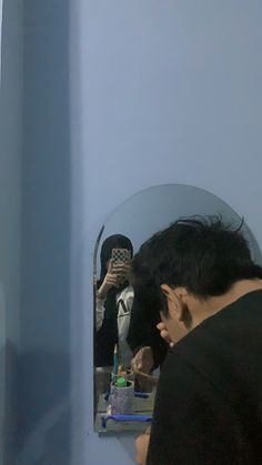 a man is looking at his reflection in the mirror