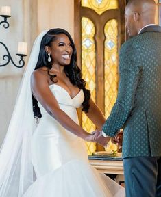 a bride and groom holding hands in front of a stained glass window