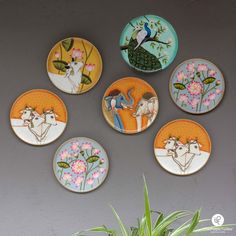 six plates with animals painted on them are hanging on the wall next to a potted plant