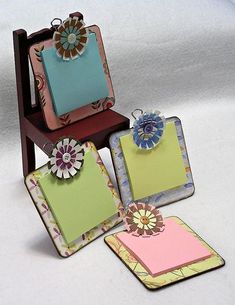 three small cards are placed next to each other on a wooden chair with paper flowers