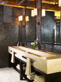 a bathroom with two sinks, mirrors and towels hanging on the wall in front of it