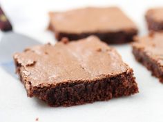 four pieces of brownie sitting on top of a white table next to a knife