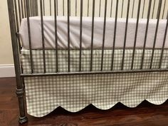 a baby crib with a white and green checkered blanket on it's side