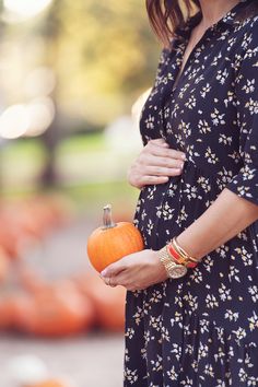 a pregnant woman holding an orange pumpkin