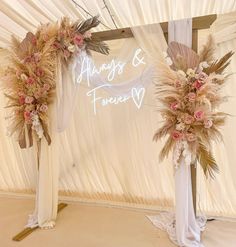 two tall floral arrangements are set up in front of a white backdrop with the word always & forever written on it