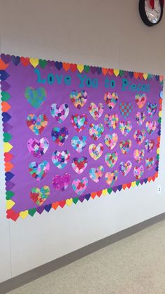 a bulletin board with hearts on it in an empty room next to a wall clock