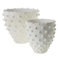 two white vases sitting side by side on a white surface with holes in them