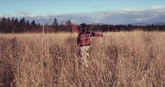 a person standing in tall grass with their arms outstretched