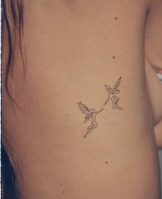 a small tattoo on the back of a woman's stomach, depicting two little tinkerbells