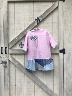 a pink shirt and blue shorts hanging on a barn door