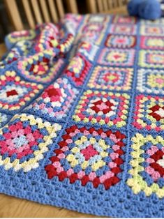 a crocheted blanket on top of a wooden table next to a stuffed animal