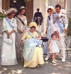 a group of people standing next to each other in front of a building with two children