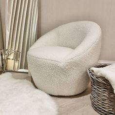 a white chair sitting on top of a wooden floor next to a basket filled with blankets