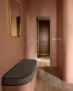 an empty hallway with pink walls and wooden floors