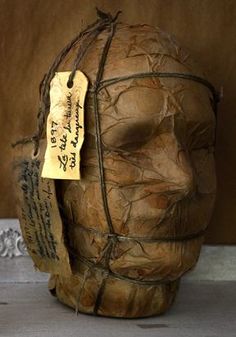 a wooden head with writing on it and a tag attached to the top of it