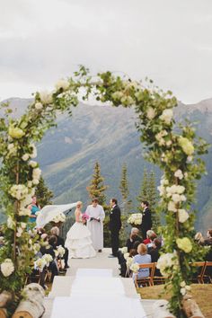 a bride and groom walking down the aisle at their outdoor wedding ceremony in the mountains