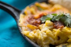 an omelet with meat, cheese and cilantro is on a blue cloth