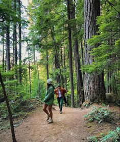 two people walking down a trail in the woods