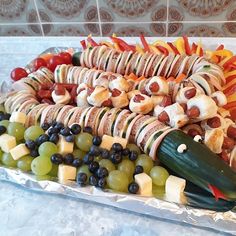 a platter filled with hot dogs, vegetables and fruit on top of tin foil