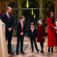 the royal family are standing in front of an alter at christmas time, dressed in red and black