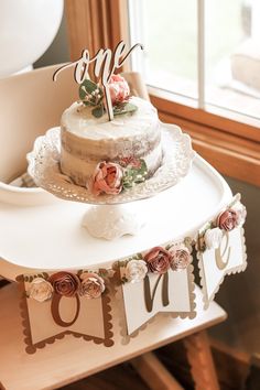 a wedding cake with flowers on it and the word love spelled in cursive letters