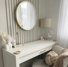 a white desk with a mirror on the wall above it and a chair next to it