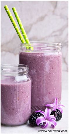 two mason jars filled with purple smoothie and blackberries