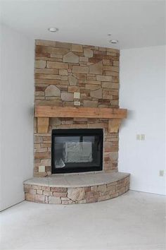 an empty room with a stone fireplace and white walls