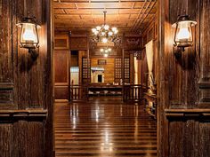 an open door leading into a room with wood paneling and chandelier hanging from the ceiling