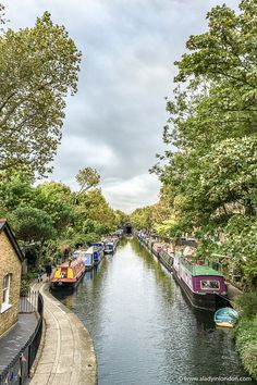 boats are lined up along the side of a narrow canal in an area that is surrounded by trees