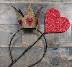 two crowns with hearts on them sitting next to each other in front of a wooden background