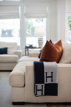 a living room with white couches and pillows on the back of it's sofa