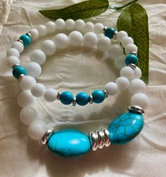 * This a definitely a "summery piece of jewelry"  * It features Turquoise stones in the oval shape as  focal, White Ceramic beads and silver details.  * It's a double strand stretchy bracelet and it measures 7 inches.  * I want you to know I strung all my stretchy bracelets with a double cord for durability and strength.  * Make sure you know to roll your stretchy bracelet in and out of your wrist, every time you wear it to avoid stretching those cords.  * I offer you free domestic shipping, and for your convenience all my orders ship with a tracking number.  * Please note that photos are taken in natural light as accurately as possible and a slight variation in sizes of handmade beads is unavoidable. * I appreciate your business and I hope you can see the attention to details I put when d Turquoise Howlite Beaded Bracelets As A Gift, Elegant Handmade Turquoise Stretch Bracelet, Turquoise Stretch Bracelet With Colorful Beads As A Gift, Turquoise Stretch Bracelet With Natural Stones For Gift, Turquoise Stretch Bracelet With Natural Stones As Gift, Turquoise Stretch Bracelet With Gemstone Beads As Gift, Turquoise Gemstone Beads Stretch Bracelet As Gift, Adjustable White Bracelet With Oval Beads, White Oval Beads Bracelet For Gift