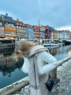 a woman is looking at the water and buildings